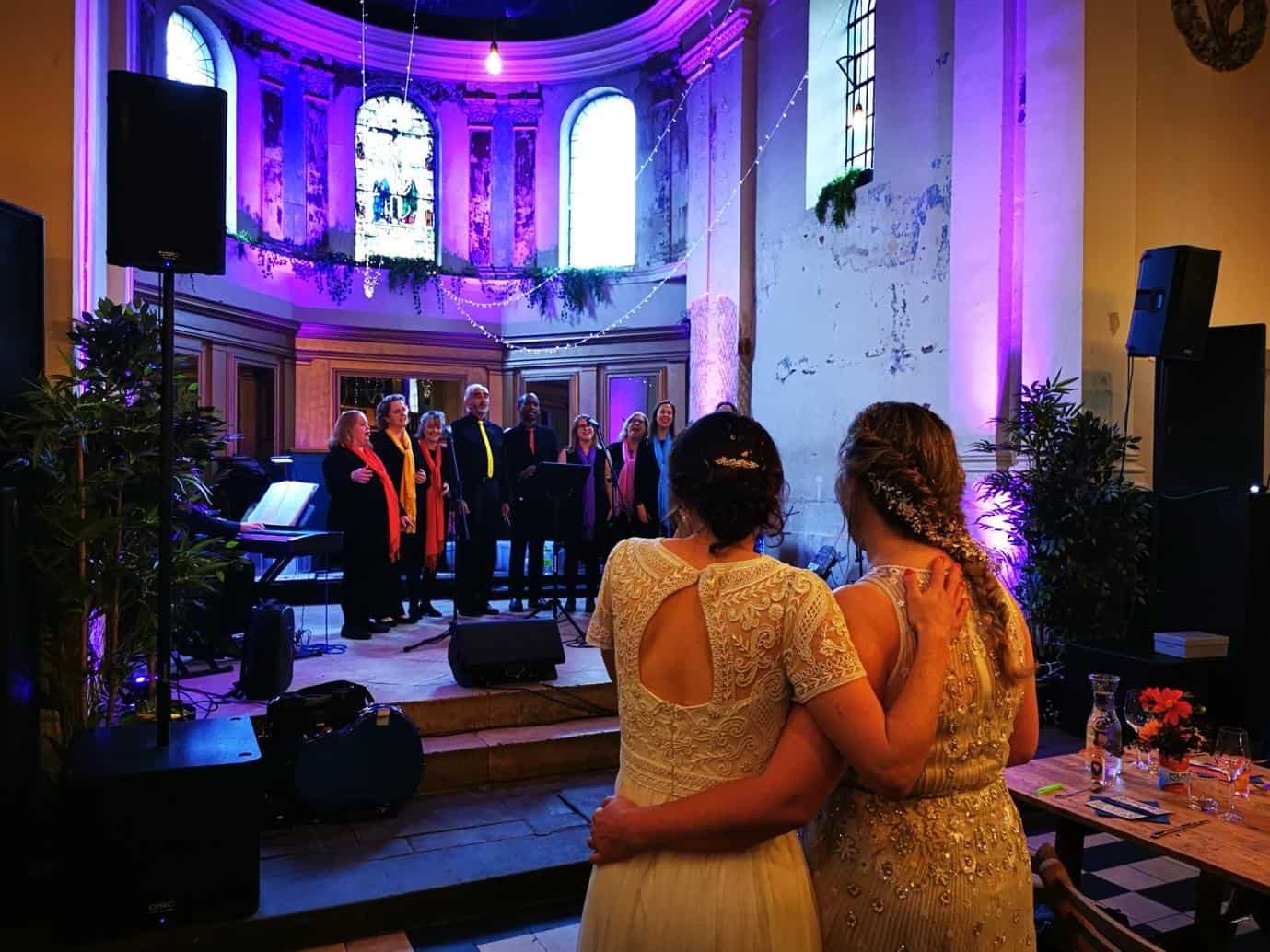 Wedding guests watching a live choir performance inside a beautifully lit chapel venue