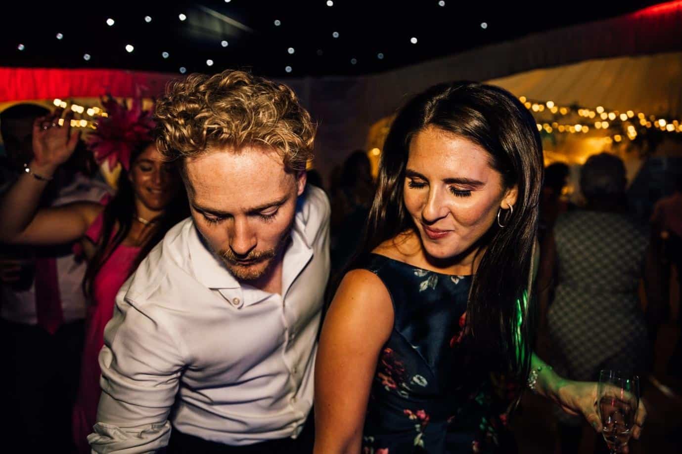 Guests dancing at a lively wedding reception party with colourful lighting and live music